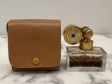 a bottle of perfume next to a small case on a marble surface