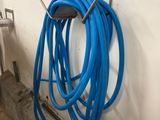 a blue hose attached to a wall next to a ladder