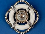 a close up of a white and gold broochle on a blue background