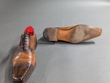 pair of men ' s brown shoes with red laces on a gray surface