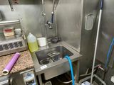 a man standing in a kitchen with a bucket and a hose