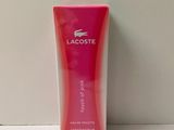 une lotion pour le corps Lacoste dans une boîte rose posée sur une surface blanche