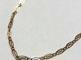a close up of a gold chain necklace on a white surface