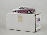 une petite voiture posée sur une boîte, sur une surface blanche