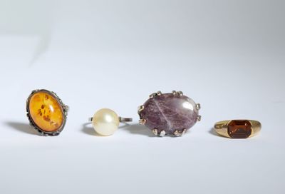 trois bagues différentes et une perle sur un fond blanc