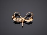 a close up of a gold bow brooch on a black surface