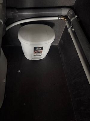 a toilet in a small bathroom with a toilet paper dispenser next to it