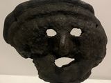 a sculpture of a face on a stand on a white surface