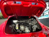 une voiture rouge dont le capot est ouvert et dont le moteur se trouve dans le coffre