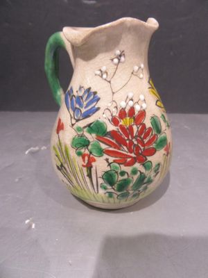 a small vase with flowers painted on it on a table