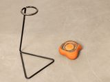 a small orange object on the floor next to a metal stand