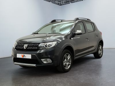 La Dacia grise est garée dans une pièce au sol noir.