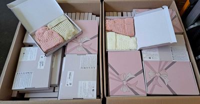 plusieurs cartons contenant des articles pour bébé, empilés dans un carton posé par terre