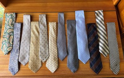 many different ties laid out on a wooden table