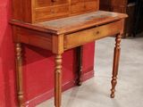 a small desk with a drawer on it in front of a red wall