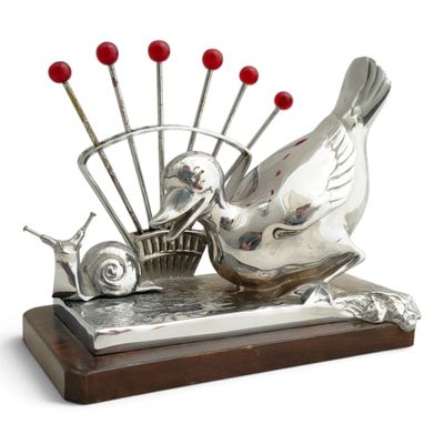 a silver sculpture of a bird and a basket of pins