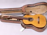 une guitare dans son étui, posée sur une surface blanche