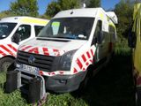 three ambulances parked in a grassy field with trees in the background
