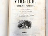 un livre ouvert posé sur une table à côté d'un mur blanc