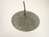 a metal sundial on a white table with a white background