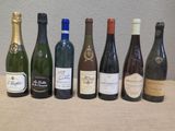 plusieurs bouteilles de vin alignées sur une table, avec un mur en arrière-plan