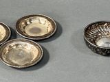 three small silver dishes and a bowl on a table