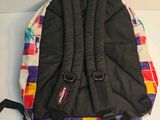 a backpack that is sitting on a bed next to a pillow