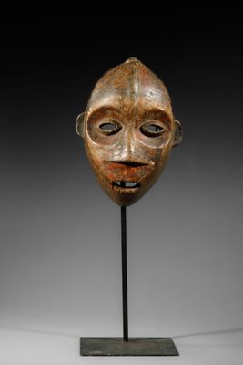 gros plan d'un masque en bois sur un support métallique