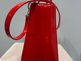 the red handbag is sitting on a white table