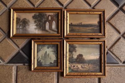 four framed paintings of a landscape on a tiled wall