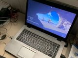 un ordinateur portable posé sur un bureau, à côté d'un clavier