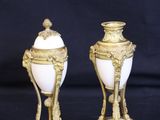 two gold and white vases sitting on top of a black table