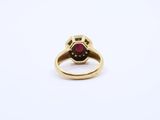 a close up of a gold ring with a red stone in it