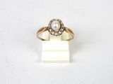 gros plan d'une bague en or avec une perle et des diamants