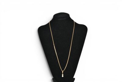 a black mannequin with a gold chain and a pearl pendant
