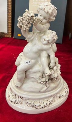 une figurine représentant un garçon tenant une grappe de raisin
