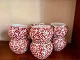 quatre vases rouges et blancs posés sur une étagère en bois