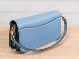 a blue purse sitting on top of a wooden table