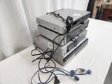 une pile d'appareils électroniques posée sur une table à côté d'un rideau blanc