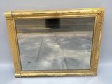 a gold framed mirror sitting on top of a white table