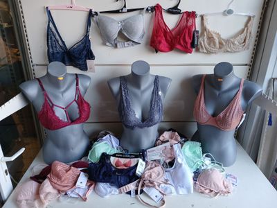 Plusieurs mannequins sont alignés sur une table devant un présentoir de soutiens-gorge