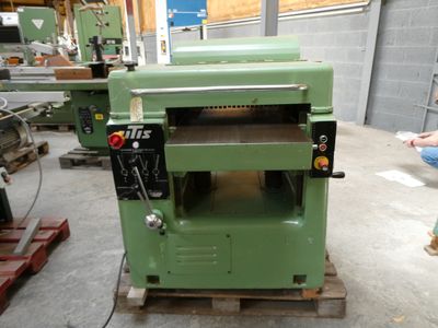 a man standing next to a green machine in a warehouse
