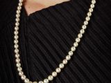 a close up of a woman wearing a pearl necklace