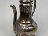 an antique silver tea pot with a bird on the handle
