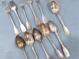 several spoons and forks are arranged in a row on a blue surface