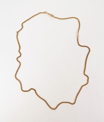 un collier à chaîne en or orné d'un petit pendentif de forme carrée sur fond blanc