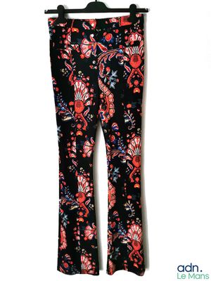 un pantalon pour femme à imprimé floral noir et rouge, suspendu à un cintre