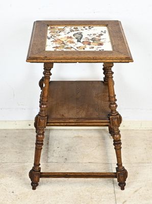 une vieille table d'appoint en bois avec un plateau en carrelage, posée sur un sol carrelé