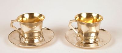 pair of silver plated cups and saucers on a white surface