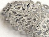a silver brooch with ornate designs on it